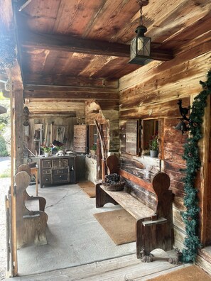 Ein rustikales Blockhaus-Interieur mit Holzwänden, einer Bank, einem Tisch und einer hängenden Laterne.