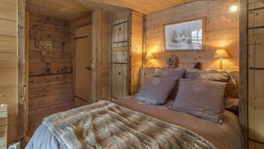 Un dormitorio de cabaña de madera con una cama, dos lámparas de noche y un cuadro en la pared.