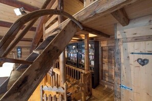 Un interior de madera con una escalera de caracol, una estantería y una puerta decorada con un corazón.