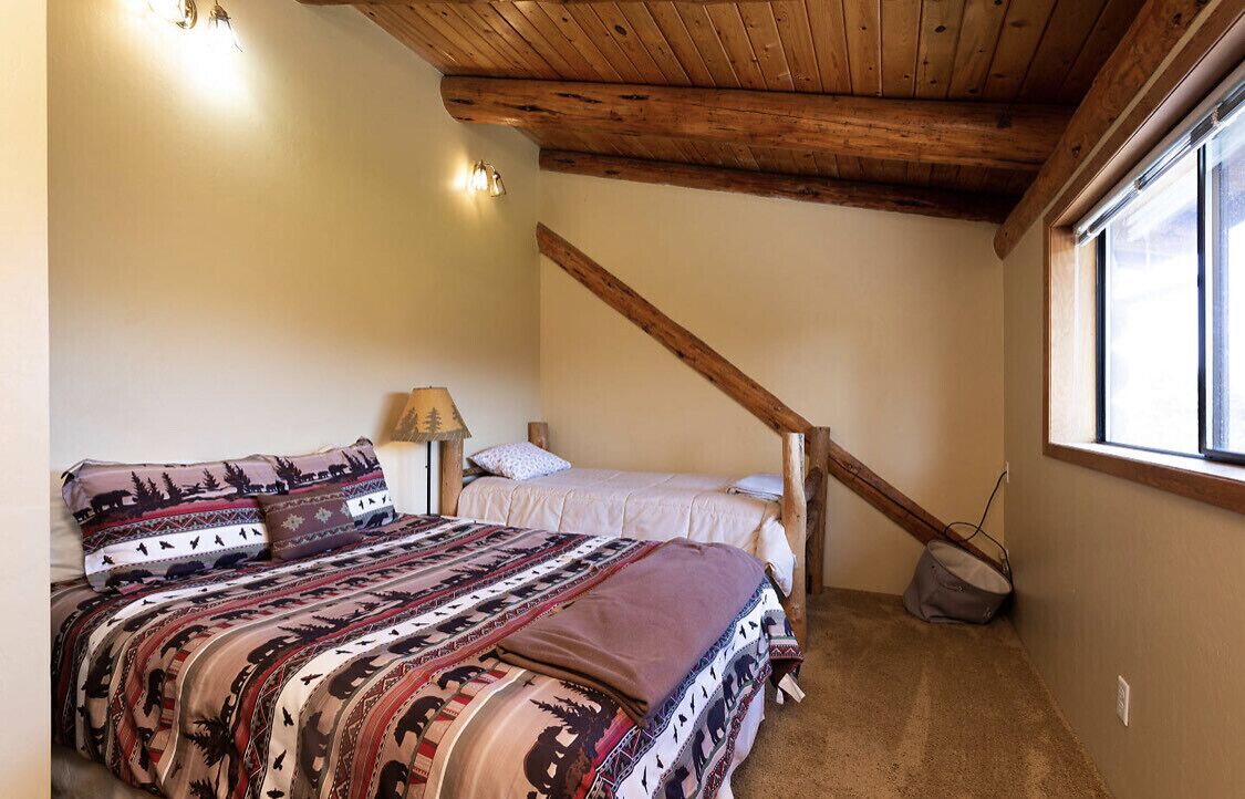 A bedroom with a bed, a nightstand, a lamp, and a window.