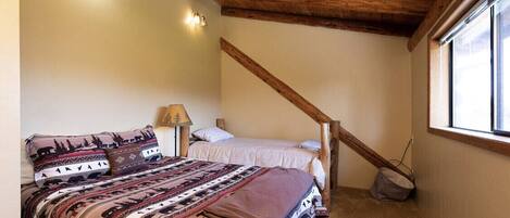 A bedroom with a bed, a nightstand, a lamp, and a window.