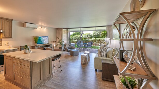 A modern kitchen with a large island, dining area with chairs, and a view of the outdoors.
