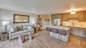 A modern kitchen with wooden cabinets, a central island with bar stools, and a dining table.