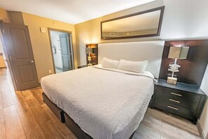 Ein Schlafzimmer mit einem großen Bett, einem Nachttisch mit Lampe und einem Spiegel über dem Bett.