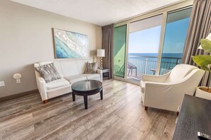 A modern hotel room with a large balcony, a white sofa, a round coffee table, and a view of the ocean. - Remodeled Direct Oceanfront, Amazing Views Modern! (Myrtle Beach)