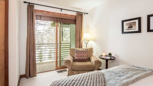A cozy room with a bed, a chair, a lamp, and a picture on the wall.