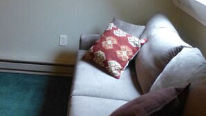 A room with a sloped ceiling, a framed picture on the wall, a couch with patterned pillows, and a visible electrical outlet. - Best Deal in Almost Heaven!! (Snowshoe)