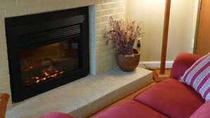 A living room with a fireplace, a red sofa, a lamp, and a mirror on the wall. - Best Deal in Almost Heaven!! (Snowshoe)