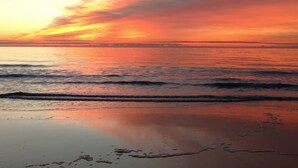 A beach at sunset with calm waves and a clear sky. - MARLIN QUAY,  2 BR , 2  bath , Unit 205, ELEVATOR,  Pools, overlooks Marina<br> (Murrells Inlet)