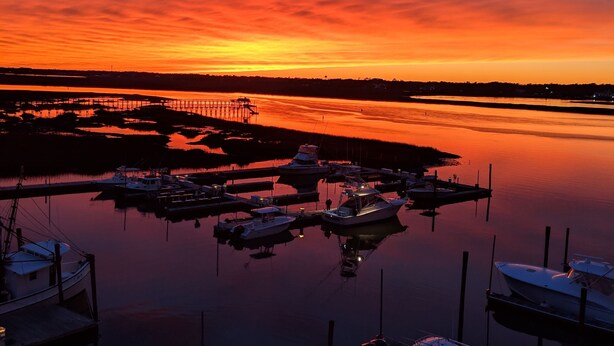 A marina at sunset with boats docked and a pier extending into the water. - MARLIN QUAY,  2 BR , 2  bath , Unit 205, ELEVATOR,  Pools, overlooks Marina<br> (Murrells Inlet)