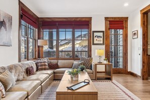 A cozy living room with a large window, a wooden coffee table, and a sofa with decorative pillows. - Outpost: Grand View 2710 - Air conditioning! (Jackson)