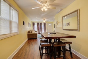 A dining area with a wooden table and benches, a ceiling fan, and a large mirror on the wall.