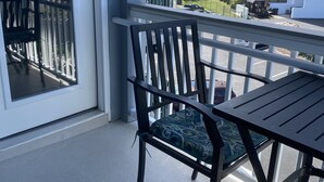 A balcony with a table and chairs, overlooking a beach and a parking area. - APATBIII Ocean Side/Ocean View 9520 SHORE DR 3P Family friendly.  (Myrtle Beach)