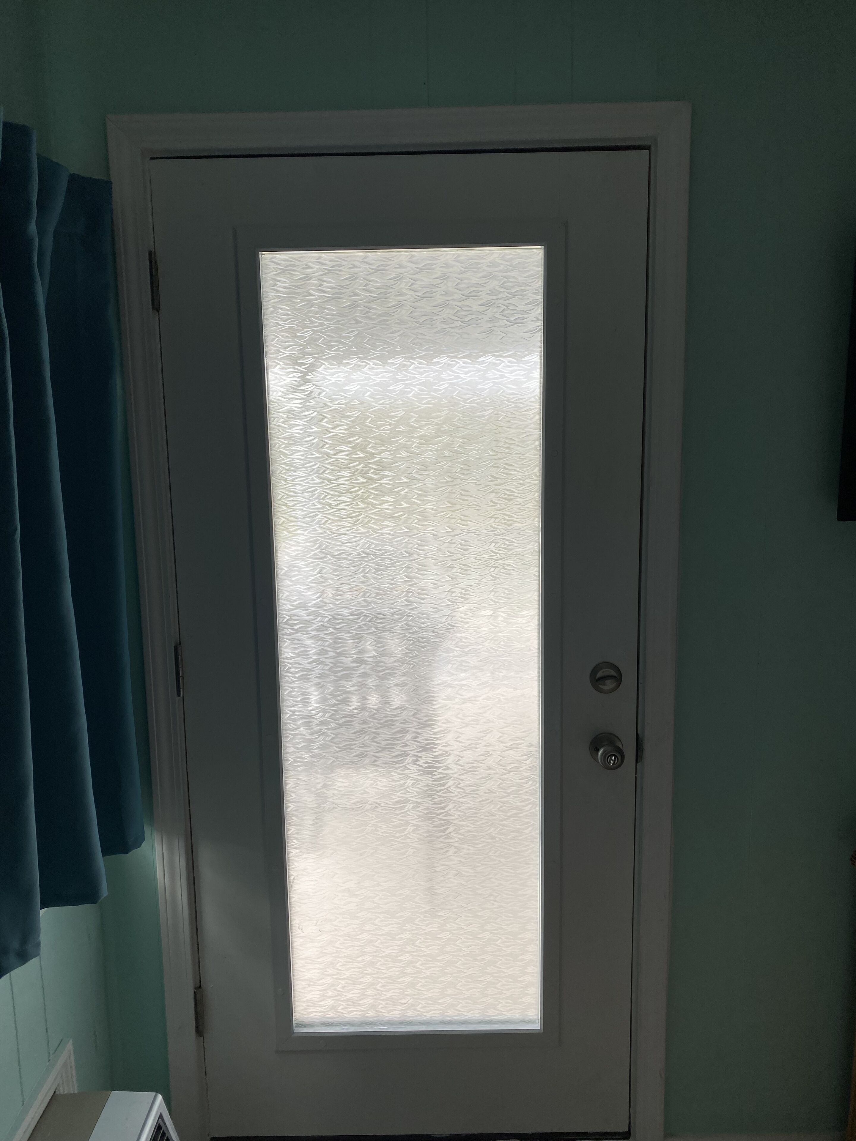 Una porta blanca amb un panell de vidre mat i una cerradura amb mirall.