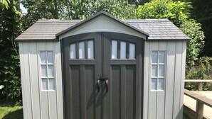 A shed with a dark gray exterior, two doors, and two windows on each side.