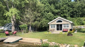 A house with a pond, a wooden dock, and a patio area with outdoor furniture.