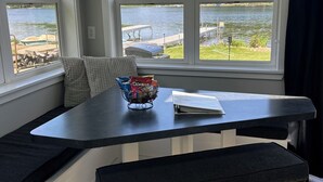 A bay window seating area with a view of a lake and dock, a chandelier, and a bowl of chips.