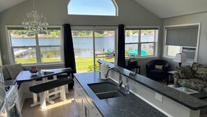 A modern kitchen with a large island, a dining area with a bench, and a view of a lake.