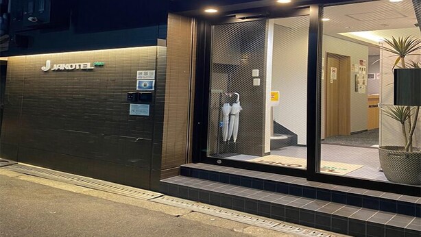 A JAKOTEL Plus hotel entrance with a modern design, including a glass door and a visible interior with a reception area. - JAKOTEL Plus Namba (Osaka)