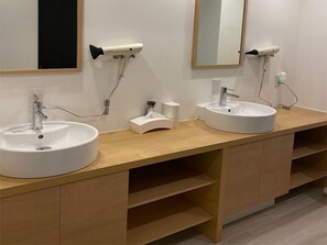 A modern bathroom with two sinks, a mirror, and a hairdryer mounted on the wall. - JAKOTEL Plus Namba (Osaka)