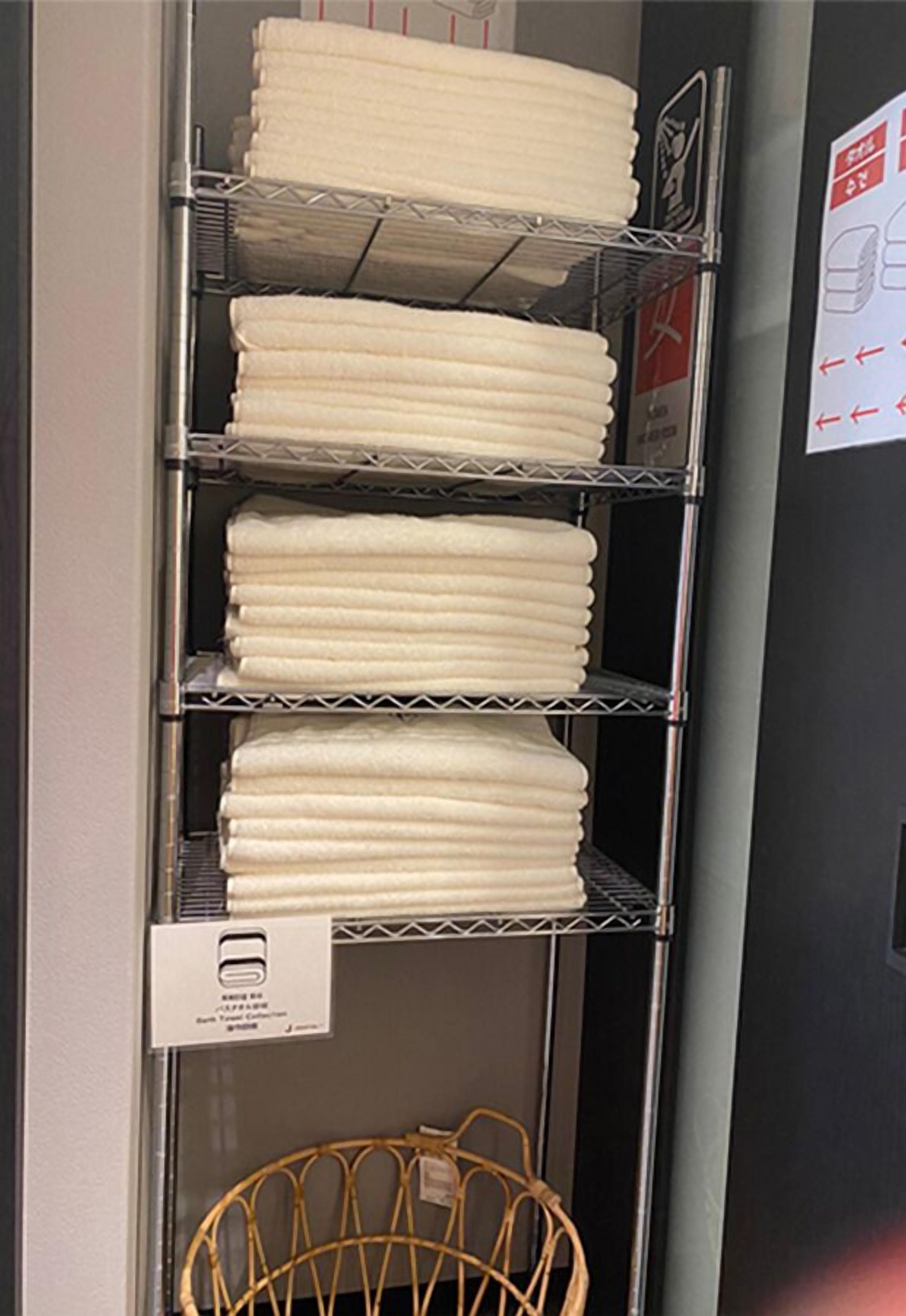 A metal shelf with neatly stacked white towels.