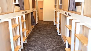 A corridor with bunk beds and storage shelves, leading to a door at the end. - JAKOTEL Plus Namba (Osaka)