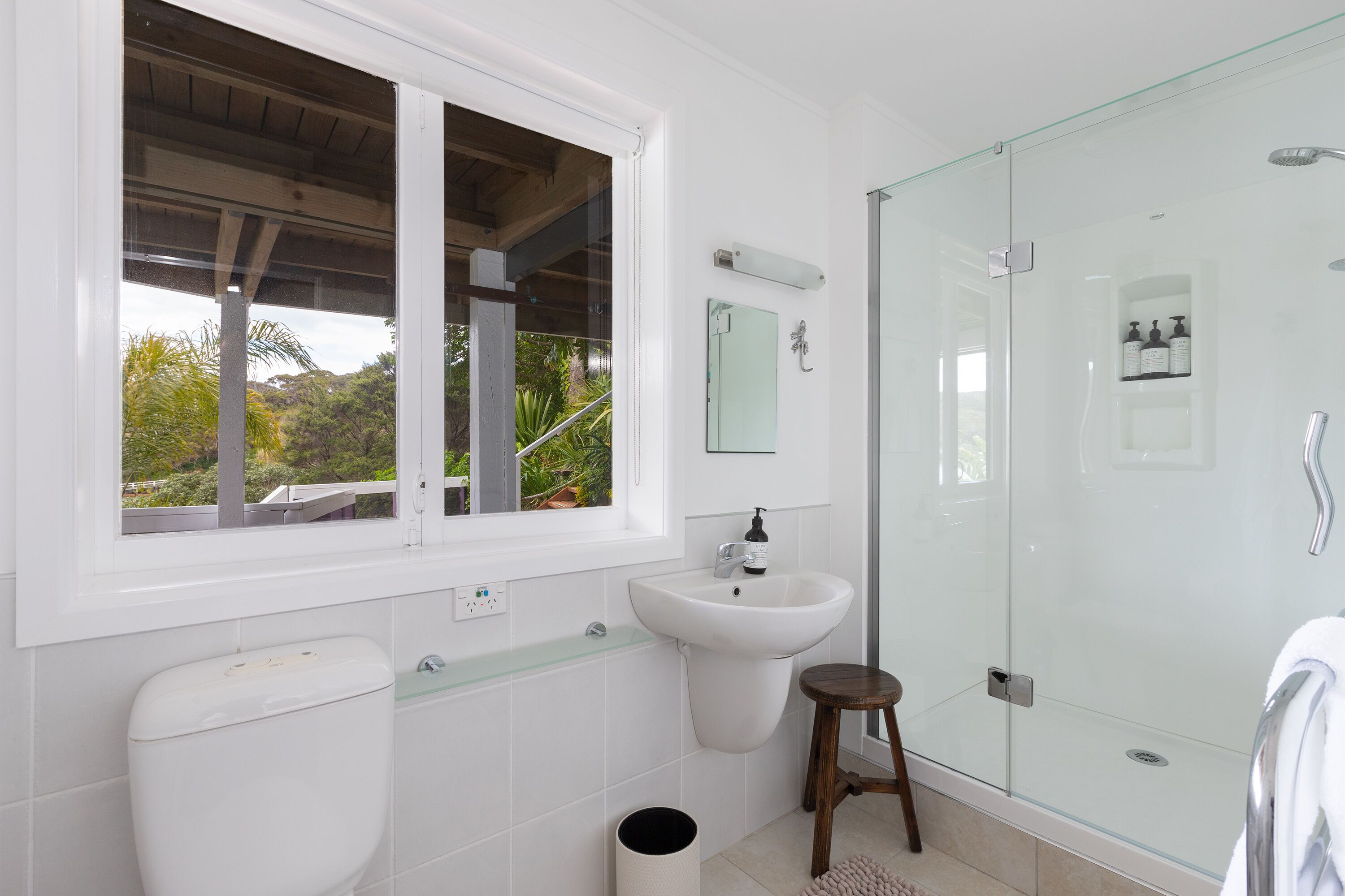 Un baño moderno con inodoro, lavamanos y ducha con cerramiento de vidrio.