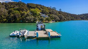 A wooden dock with a small building labeled "Kawau Lodge" and a boat moored at the dock. - Kawau Lodge Boutique Resort (Kawau Island)