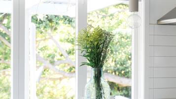 A kitchen with a white countertop, a vase with greenery, and a fruit bowl.
