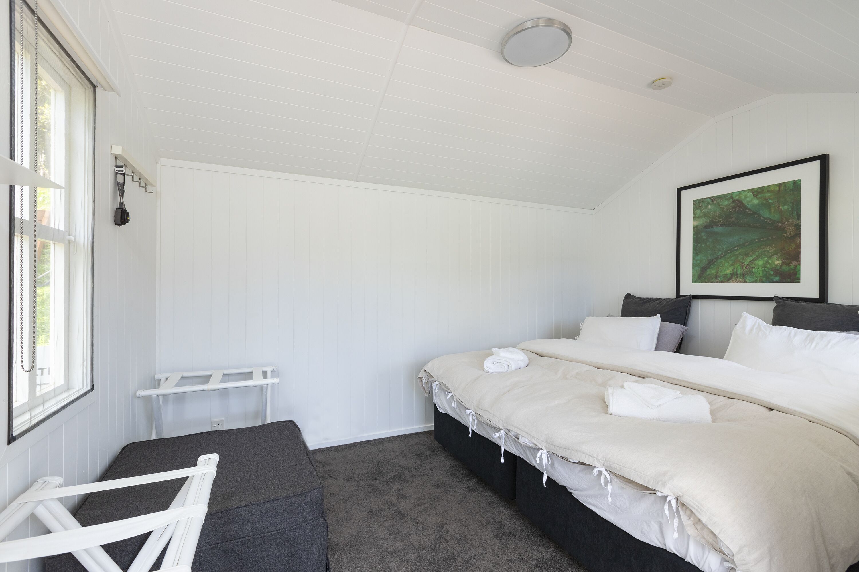 Un dormitorio con una cama grande, una ventana, un techo blanco y un cuadro en la pared.
