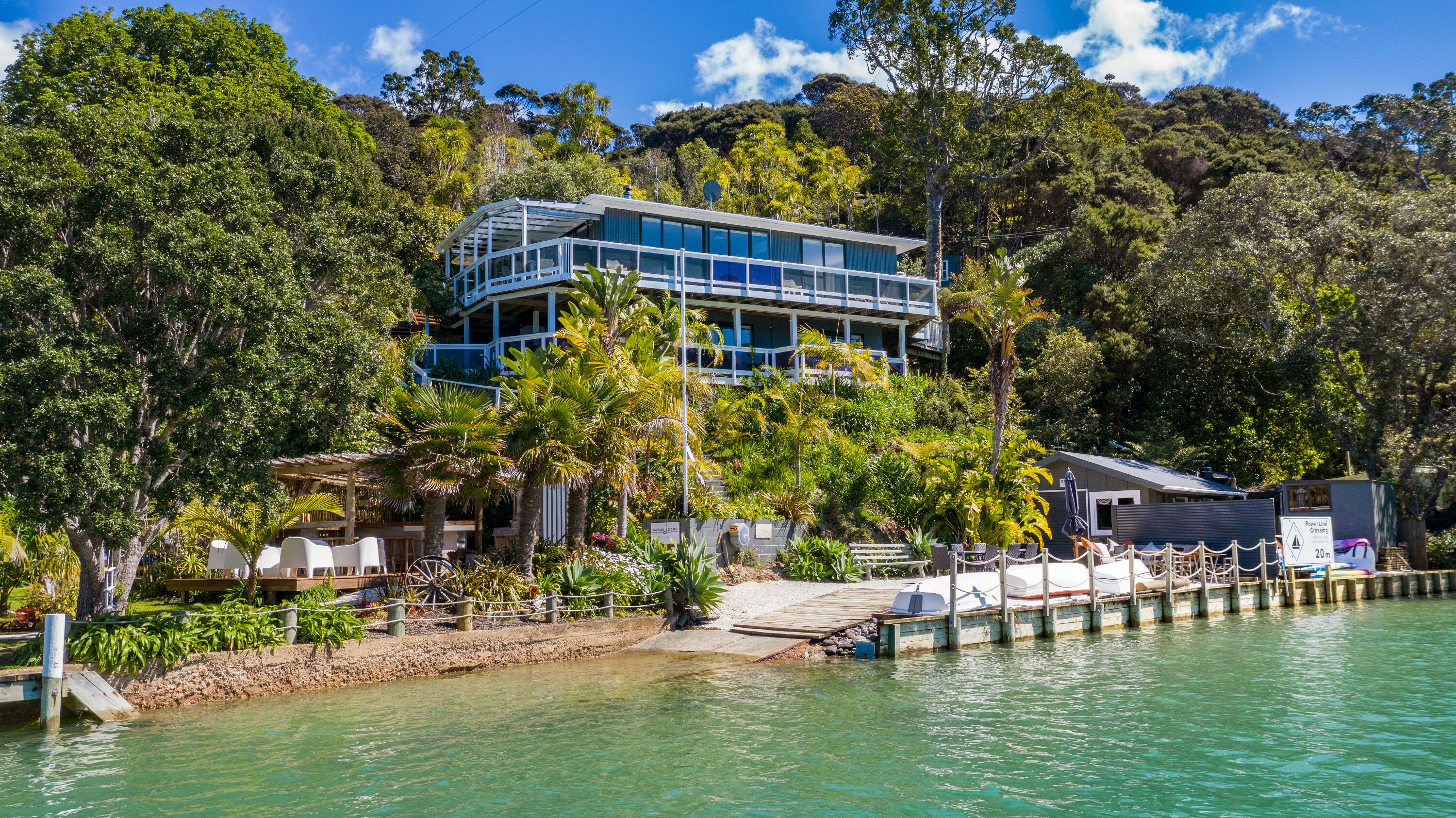 Un bâtiment moderne à plusieurs étages, entouré d’une végétation luxuriante et situé au bord de l’eau.