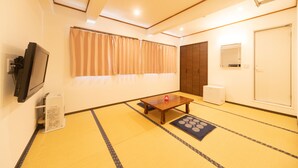 Una habitación con suelo de tatami, una mesa de madera, un televisor y una puerta corredera.