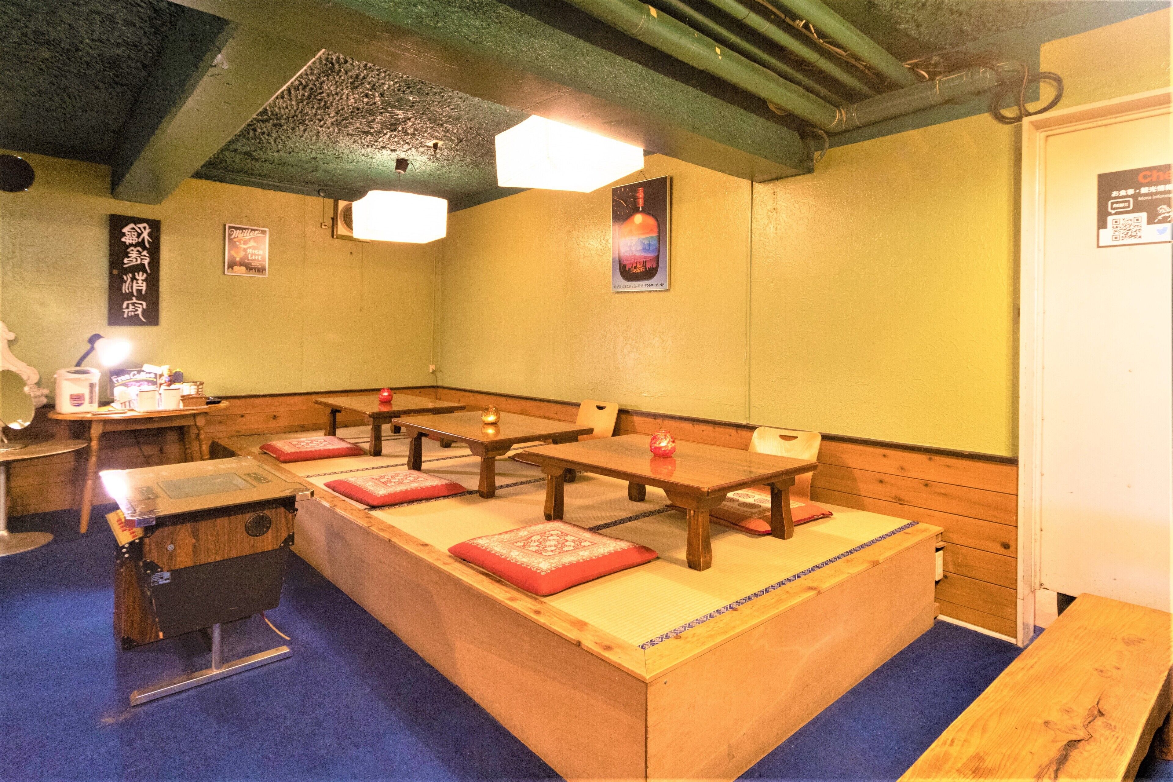 Una habitación tradicional japonesa con tatamis, mesas y bancos de madera.