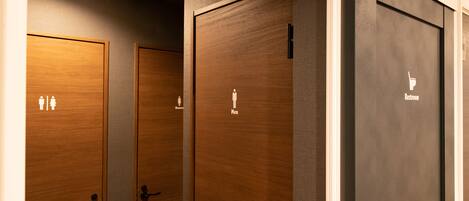 A row of wooden and black restroom doors with gender-specific signage.