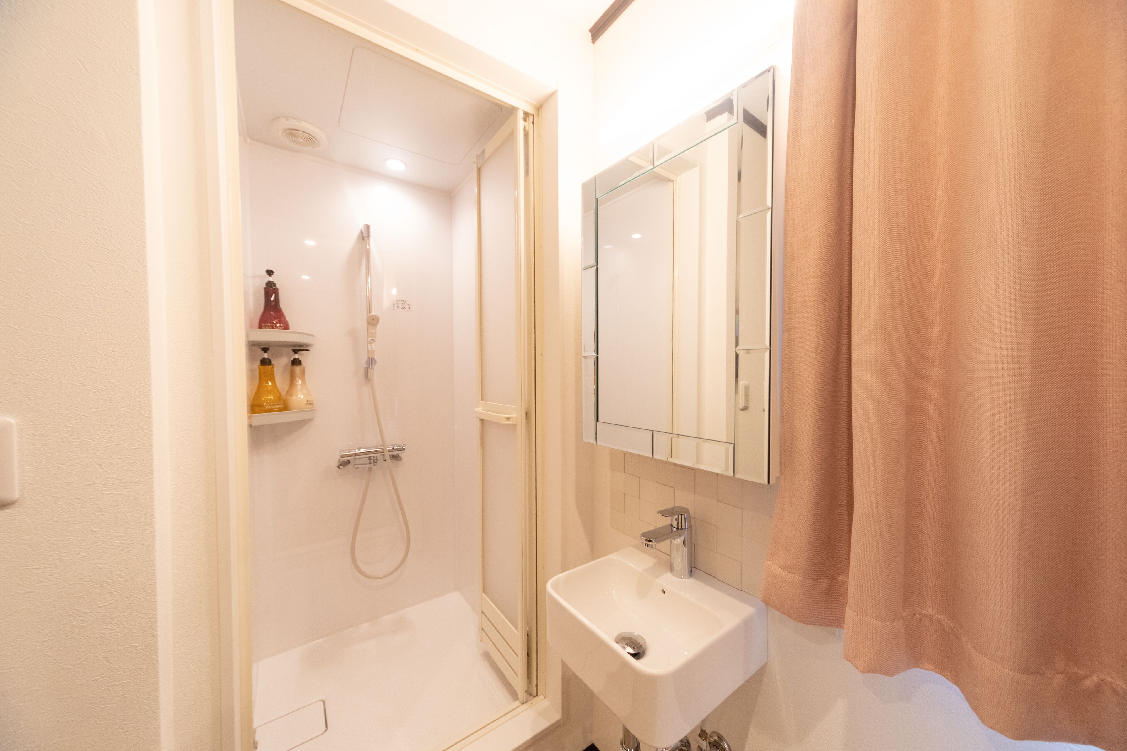 Een badkamer met een douche, wastafel en spiegel.