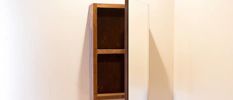 Um armário de madeira fixado na parede, com um painel branco, provavelmente para guardar ou expor objetos.