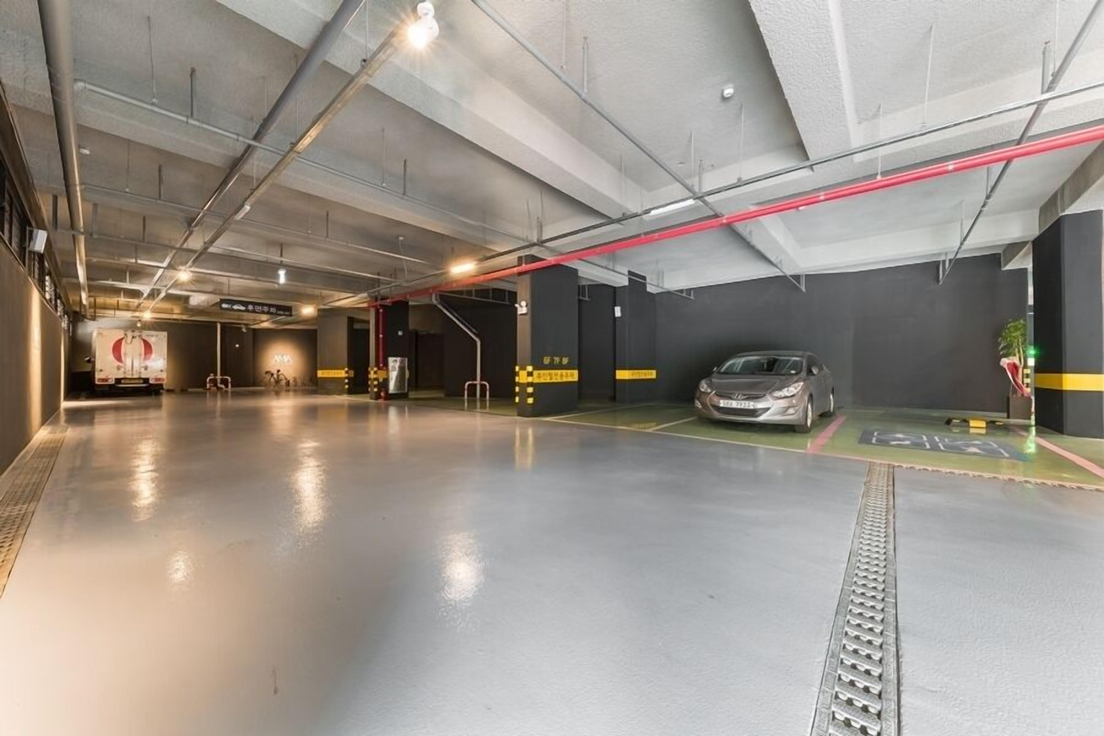 A modern indoor parking garage with a clean, polished floor and a single car parked.