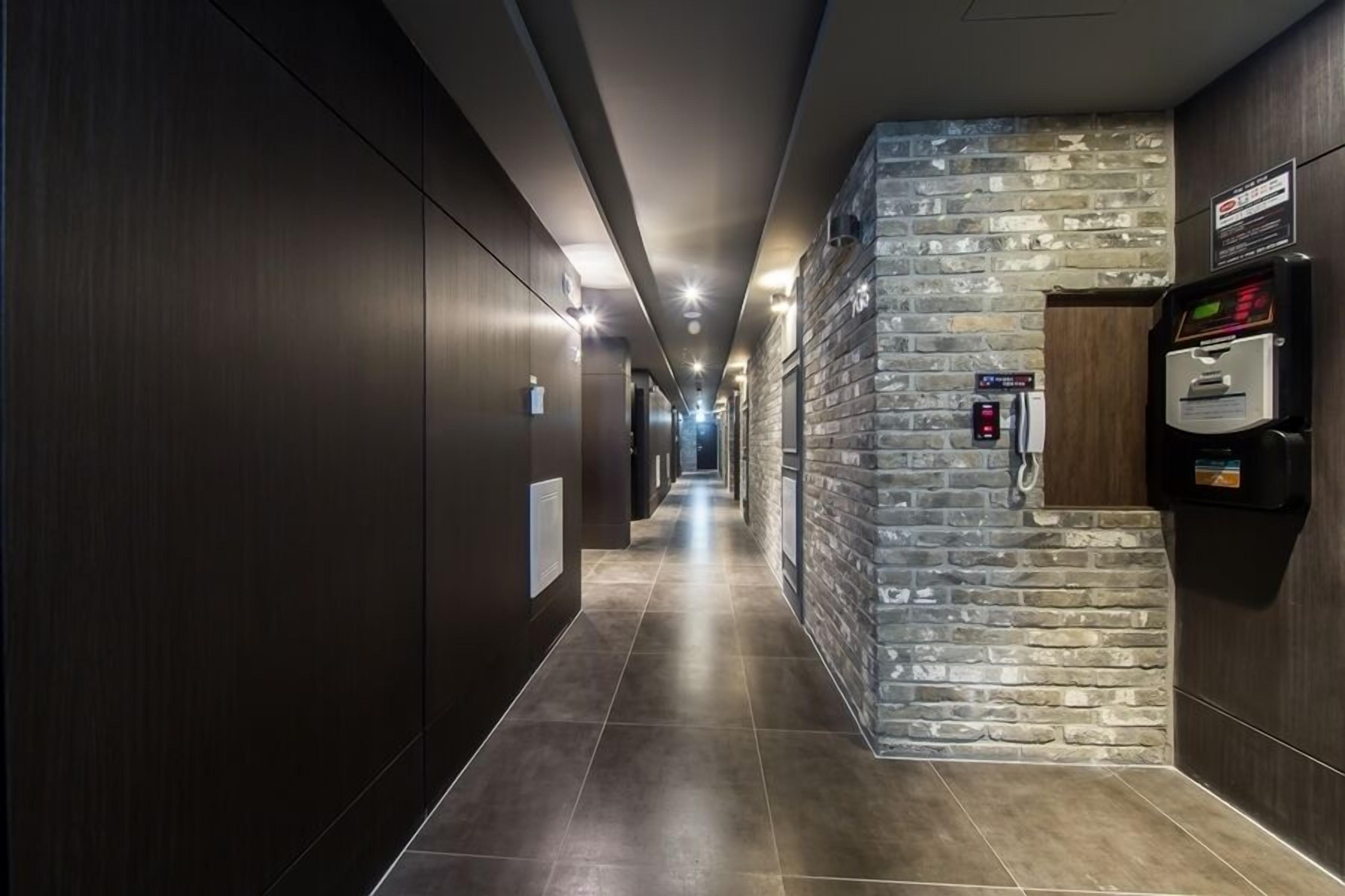 A modern hotel corridor with a stone accent wall, a vending machine, and a fire alarm.