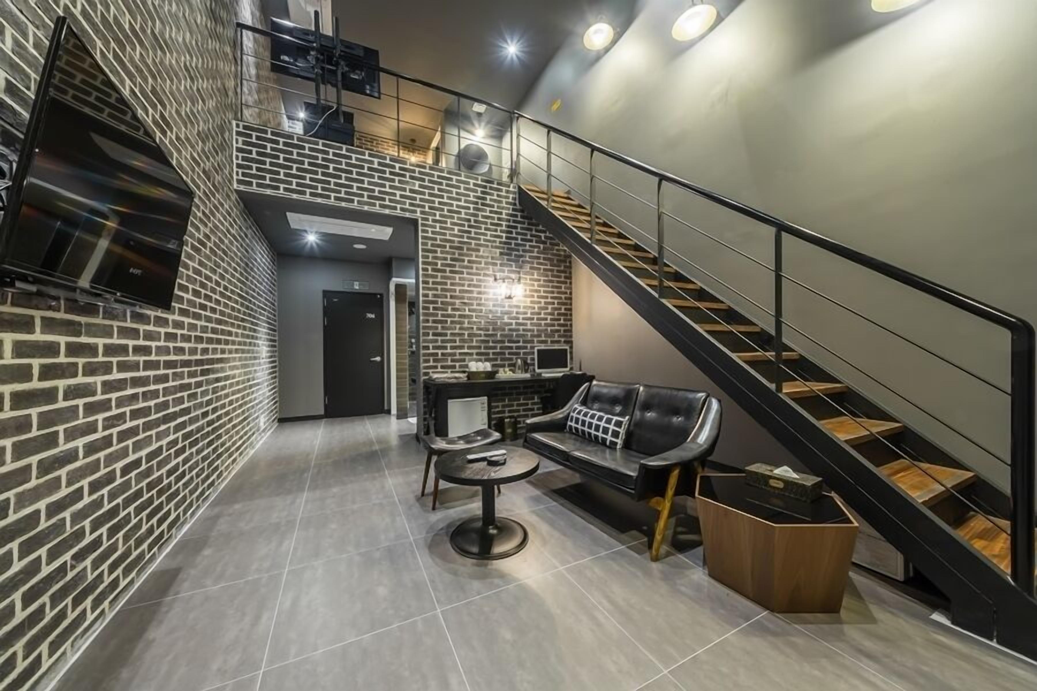 A modern interior with a brick wall, a staircase, a sofa, and a coffee table.