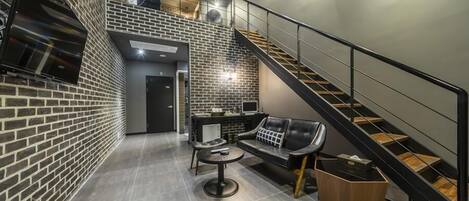 A modern interior with a brick wall, a staircase, a sofa, and a coffee table.