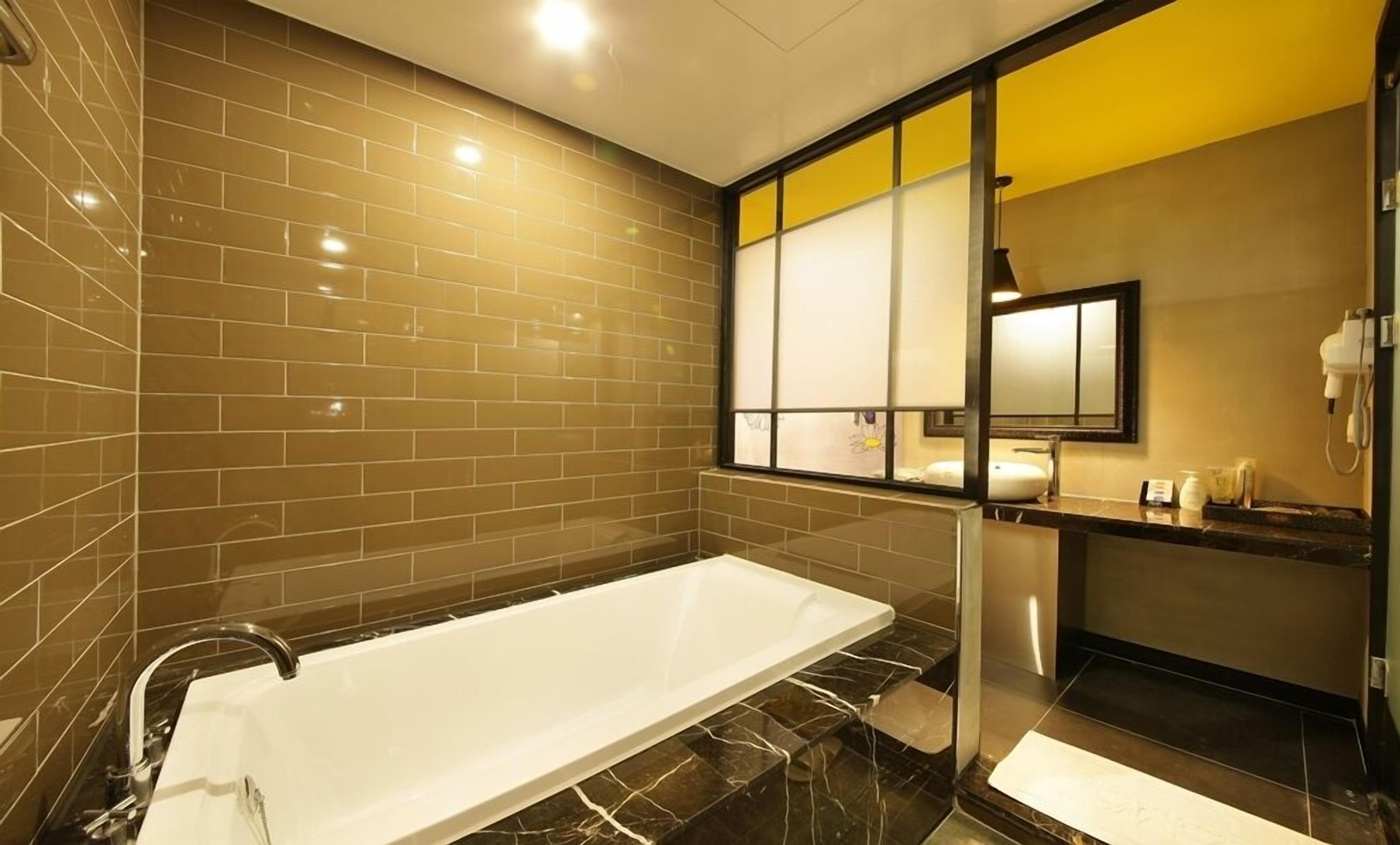 Een moderne badkamer met een groot ligbad, een douchecabine van glas en een wastafel met spiegel en toiletartikelen.