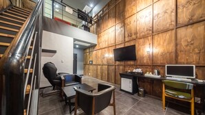 Een moderne werkruimte met een bureau, stoelen, een televisie en een trap.