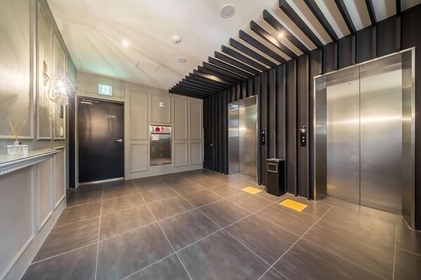 A modern elevator area with a sleek design, including a metallic elevator and a wall-mounted control panel. - Anyang Boutique Hotel AMA (Anyang)