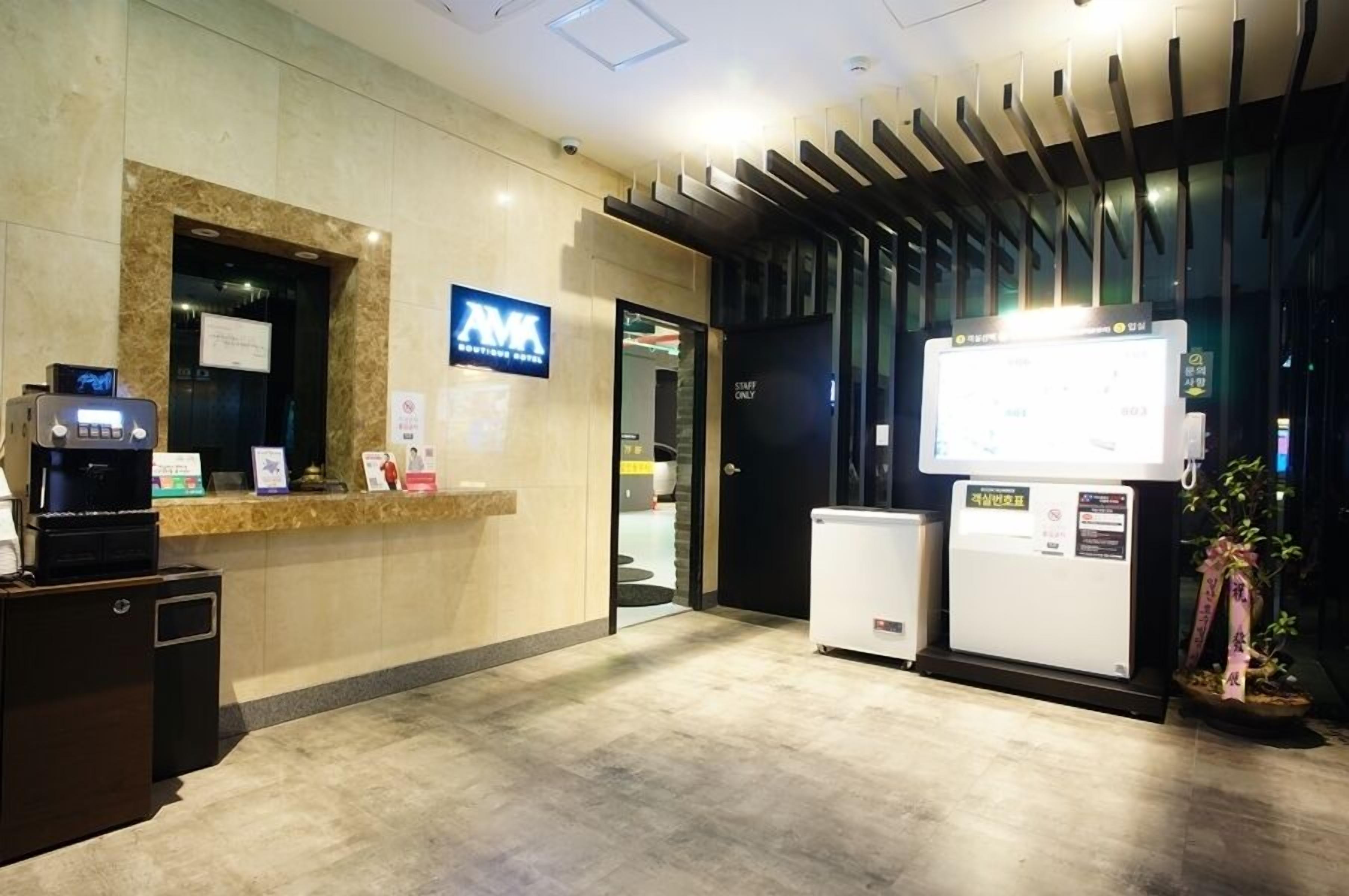 Zona de recepción de hotel con mostrador de mármol, pantalla digital y letrero que indica acceso 'Solo personal'.