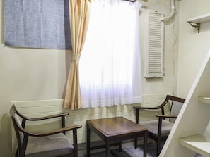 A room with two wooden chairs, a small table, a window with curtains, and a radiator. - Pension Ohayo (Hakuba)