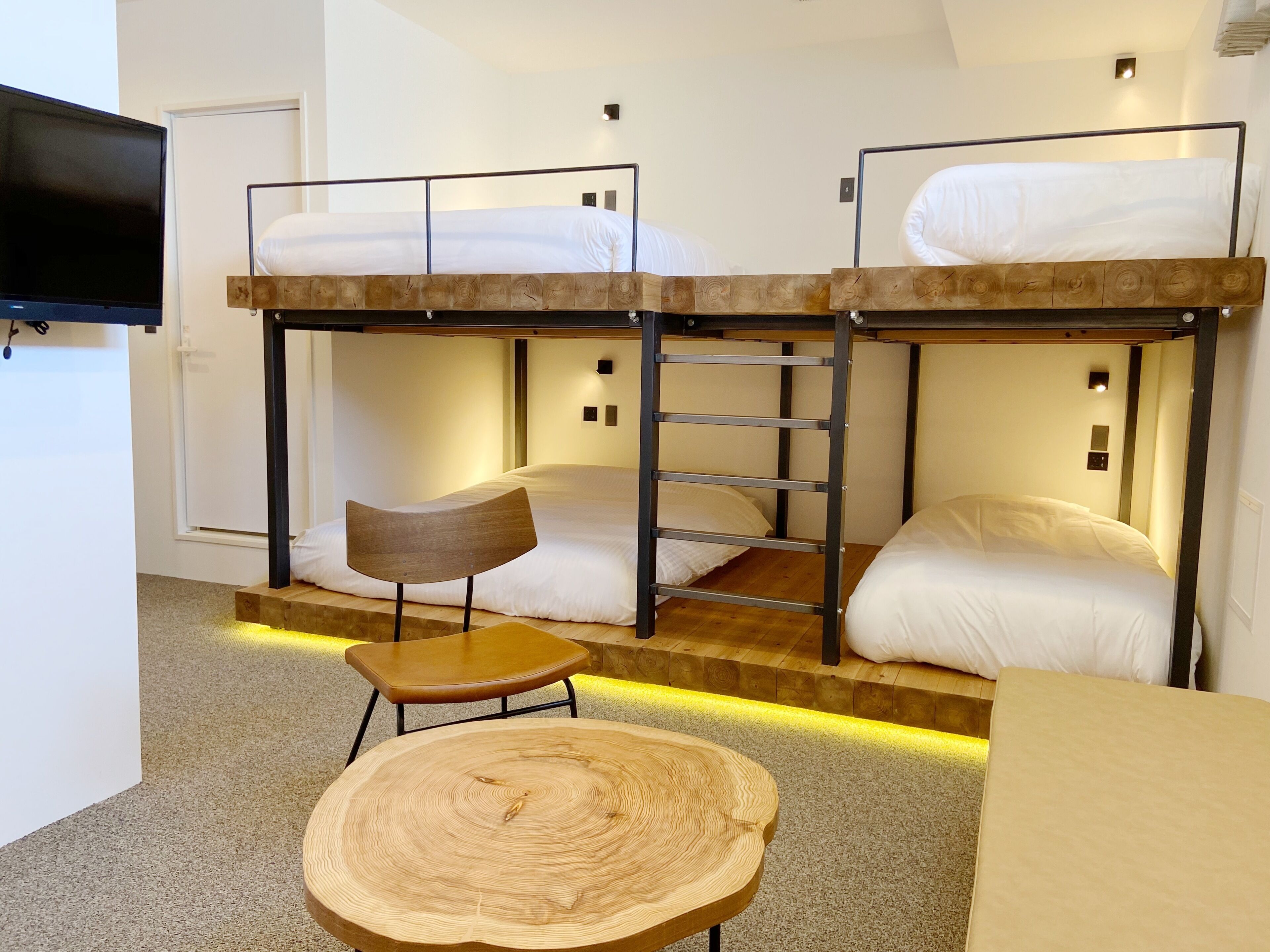 A bunk bed room with a wooden table and a chair.