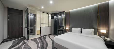 A modern hotel room with a large bed, a desk, a chair, and a walk-in closet.