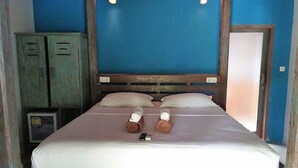 Ein Bett mit Holz-Kopfteil, zwei Kissen und zwei zusammengerollte Handtücher.