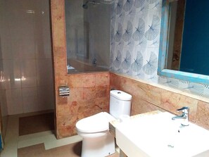 A bathroom with a toilet, sink, and shower area. - Mahaputri Bungalow (Gili Trawangan)