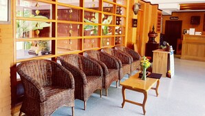 A reception area with wicker furniture, a wooden reception desk, and a sign for the toilet and shower. - Bagan View Hotel (Nyaung-U)